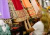 A shopper choosing a preloved embroidered lehenga in a South Asian fashion boutique