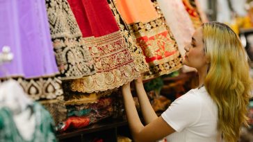 A shopper choosing a preloved embroidered lehenga in a South Asian fashion boutique