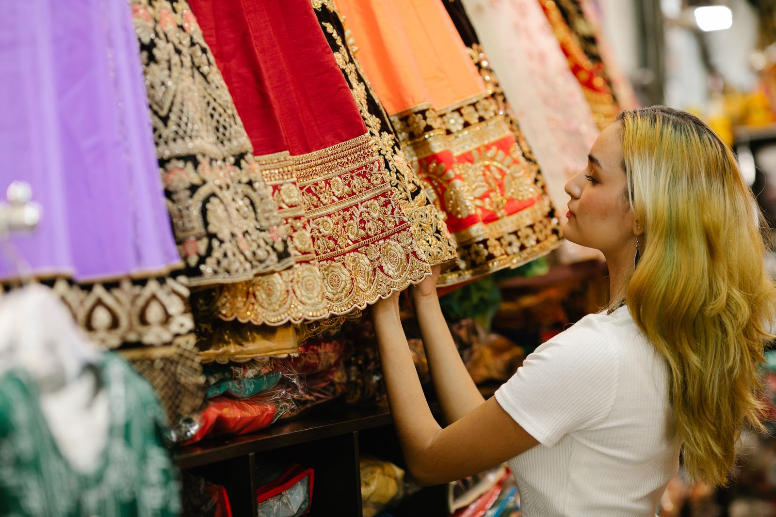 A shopper choosing a preloved embroidered lehenga in a South Asian fashion boutique